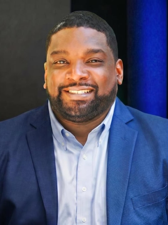 Eugene Hamilton smiling, in a blue blazer